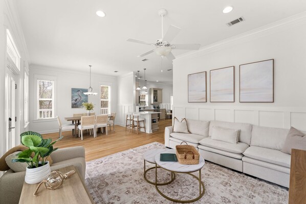 A spacious living room with a sofa, coffee table, and a dining area with chairs and a table. - Coastal 30A Retreat - 4BR - Sleeps 8 - Walk to Beach (Santa Rosa Beach)