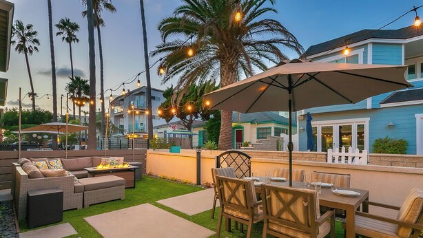 An outdoor patio with a fire pit, seating, and string lights. - Grand 5BD Tri-Level Home with Bay Views Garage Parking AC & Large Patio! (San Diego)