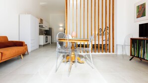 Un soggiorno moderno con angolo pranzo, divano, televisore e cucina sullo sfondo.
