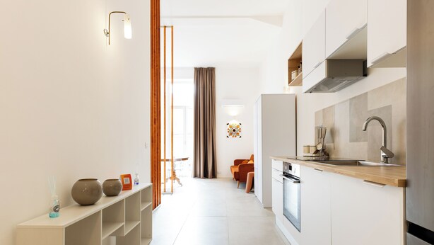 Una cucina moderna con mobili bianchi, una cappa in acciaio inossidabile e un piano di lavoro in legno.