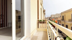 Un balcone con vista su una strada cittadina, una ringhiera e una pianta in vaso.