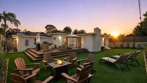 Ein Garten mit Feuerstelle, Gartenmöbeln und einer Terrassenfläche.