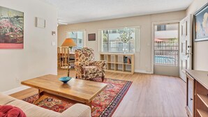 Un salón con una mesa de centro de madera, un sillón estampado y una estantería.