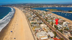 Un paysage urbain côtier avec une plage, des immeubles résidentiels et un port de plaisance.