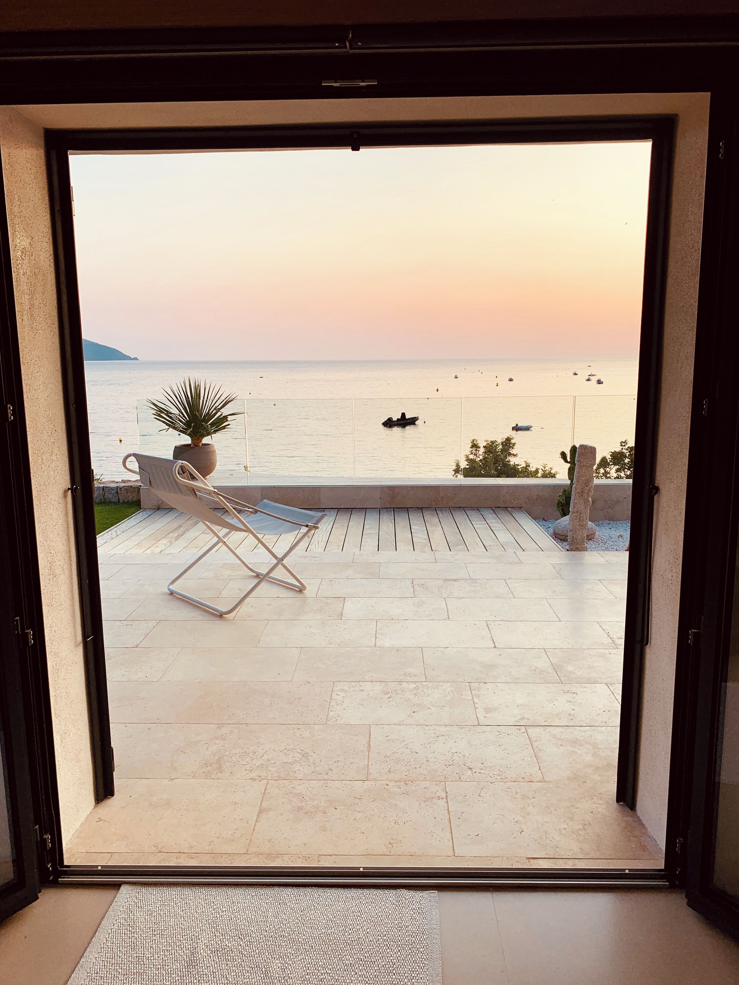 Un balcón con vista al mar, una silla y una planta en maceta.
