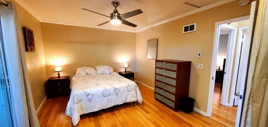 A bedroom with a bed, nightstands, a dresser, and a ceiling fan.