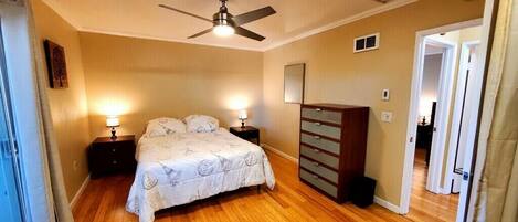 A bedroom with a bed, nightstands, a dresser, and a ceiling fan.