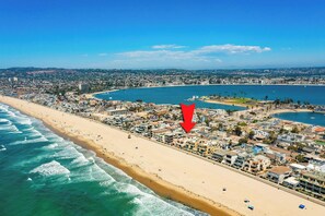A coastal cityscape with a beach, buildings, and a large body of water.