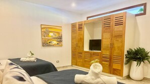 A hotel room with two beds, a wooden wardrobe, a TV, and a painting on the wall. - Brisa Azul | Poolfront | Walk to Beach | Wi-Fi (Las Terrenas)