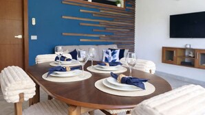 A dining area with a wooden table set for four, white plates, and blue napkins. - Brisa Azul | Poolfront | Walk to Beach | Wi-Fi (Las Terrenas)