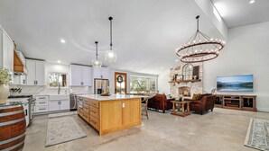 Una cocina amplia con una isla central, armarios blancos y una chimenea de piedra.