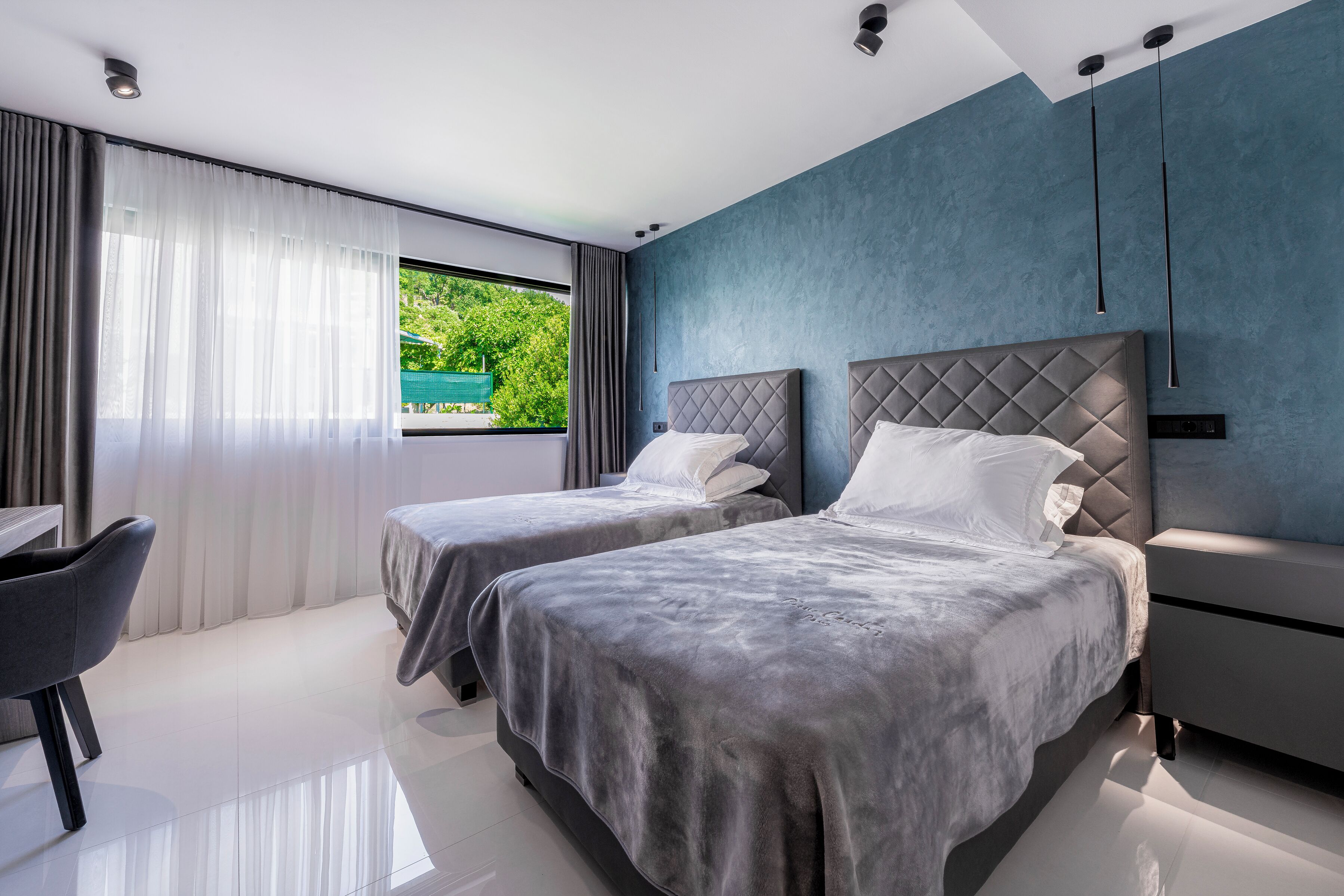 Una habitación de hotel moderna con dos camas, un escritorio y vistas a zonas verdes.