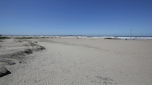Una amplia playa de arena con cielo azul despejado.
