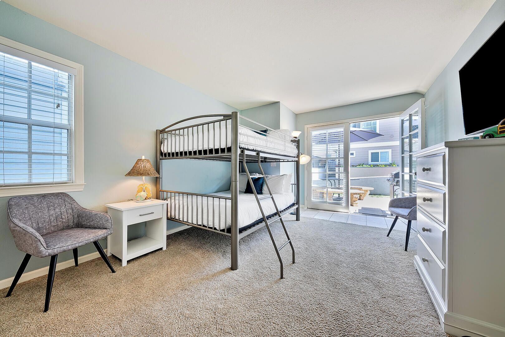 A bunk bed room with a desk, chair, and a view of the outside.
