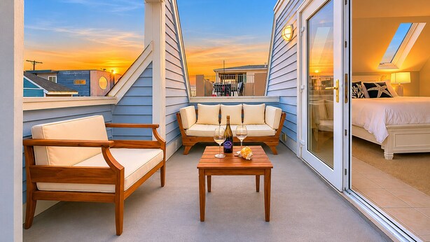 A balcony with a sofa, chairs, and a table with wine glasses and a bottle. - Perfect For Families, Steps To Beach, Close to Everything! (San Diego)