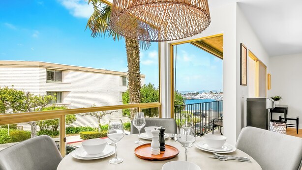 A dining area with a table set for four, a salt and pepper shaker, and a view of a cityscape through large windows. - Pet Friendly 2 bedroom in Point Loma Overlooking Kellogg Beach - Stay for 30 days! (San Diego)
