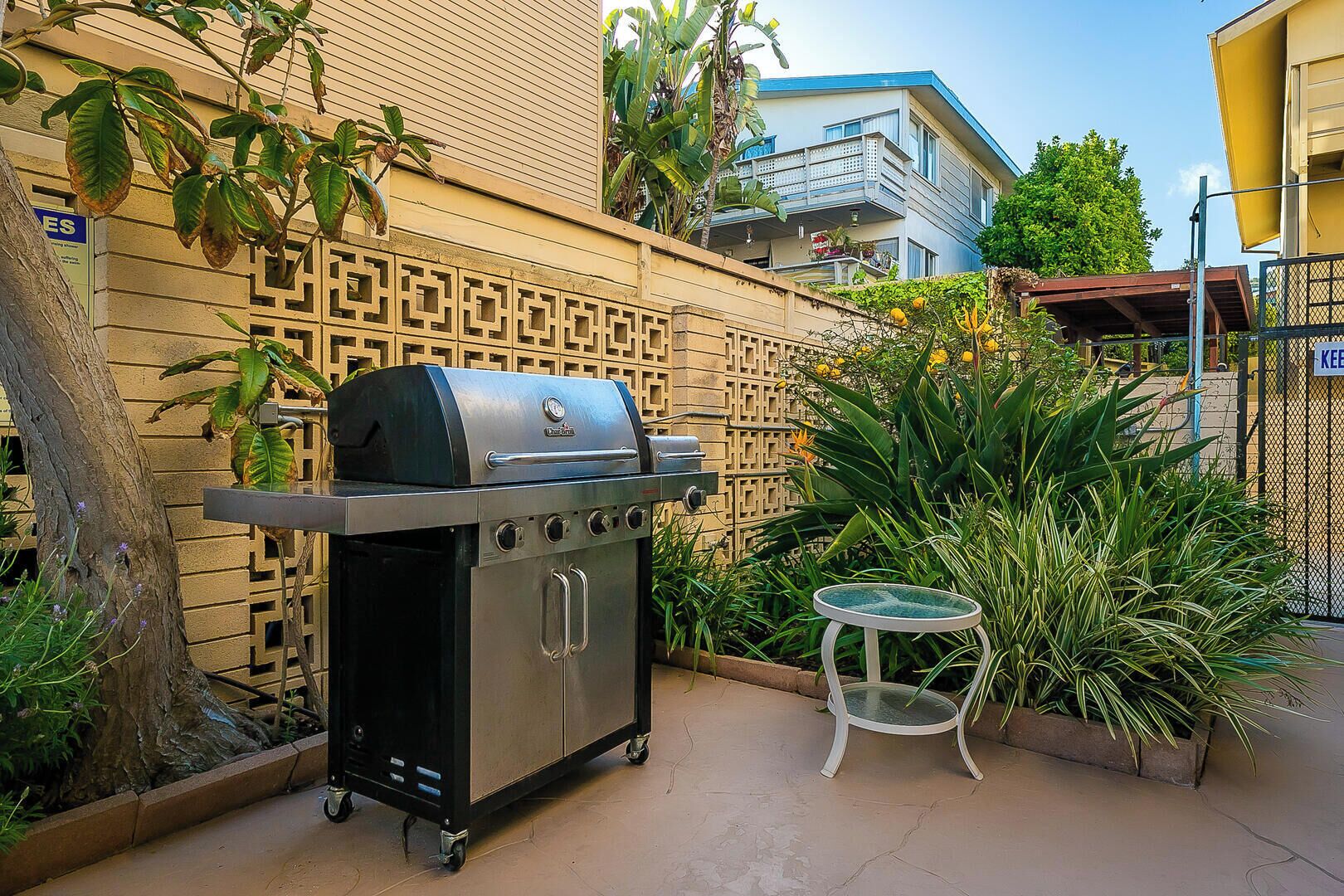 A patio with a portable grill, a small table, and a decorative fence.