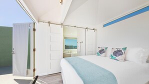Un dormitorio con cama, ventana, baño y puerta.