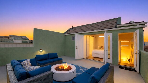 Una terraza en la azotea con un brasero, mobiliario exterior y un dormitorio con puerta corrediza.