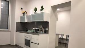 A modern kitchen with a built-in oven, a sink, and a small dining area with two chairs.