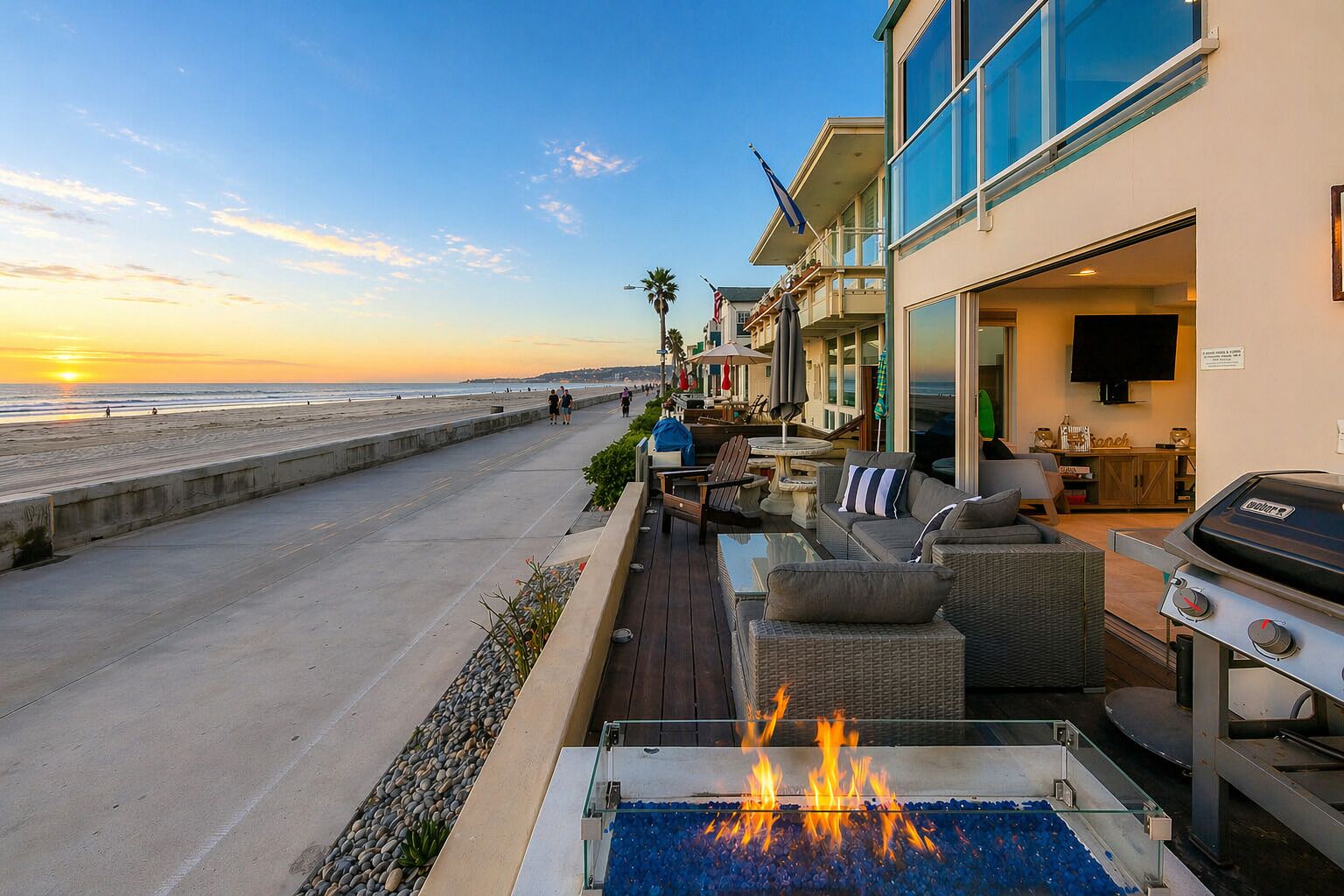 A seaside patio with outdoor seating, a grill, and a fire feature.