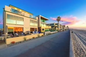 Ein modernes Hotel mit Poolbereich, Außenbereich zum Sitzen und Blick auf den Strand bei Sonnenuntergang.