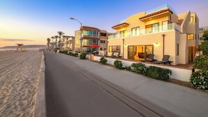 Et strandhotel med moderne design, der har et poolområde med liggestole og et overdækket opholdsområde.