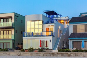 A multi-story residential building with a balcony, a staircase, and a garage. - 3BD Oceanfront Ground Floor Escape in Mission Beach! Steps from the Ocean! On Boardwalk with Parking! (San Diego)