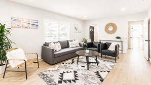 Een moderne woonkamer met een grijze modulaire bank, een ronde salontafel en een zwarte lederen fauteuil.