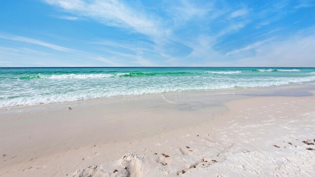 Ein Strand mit blauem Himmel und ruhiger Wellenbewegung.