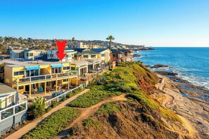 A coastal residential area with multi-story houses, a clear view of the ocean, and a rocky shoreline. - Ocean Front, Amazing Reviews, Best 2BR in San Diego! (San Diego)