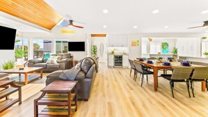 A modern living room with a sofa, coffee table, and dining area with chairs and a table. - Perfect for Families,Steps to the Beach W/Parking! (San Diego)