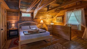 A cozy log cabin bedroom with a wooden bed, bedside lamps, a window with curtains, and a small picture on the wall. - Waterfront Victoria Cottage,Kayaks,paddle board and canoe Included, Dogs Welcome (Clifton)
