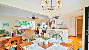 A dining area with a wooden table set for four, a chandelier, and a view of the kitchen and living room. - Great for Families, Easy Walk to Beach, Pet Friendly! (San Diego)