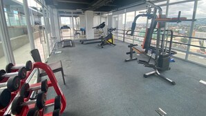Een sportschool met diverse fitnessapparaten, grote ramen en uitzicht over de stad.
