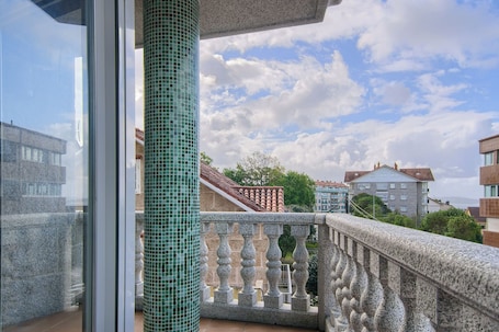 A balcony with a stone balustrade and a view of surrounding buildings.