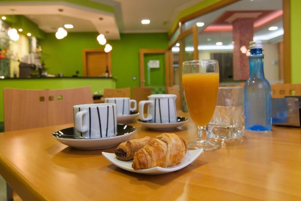 A breakfast setting with croissants, coffee cups, and a glass of orange juice on a table.