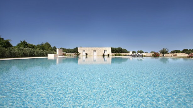 Une grande piscine aux eaux claires, avec un bâtiment visible à l’arrière-plan.
