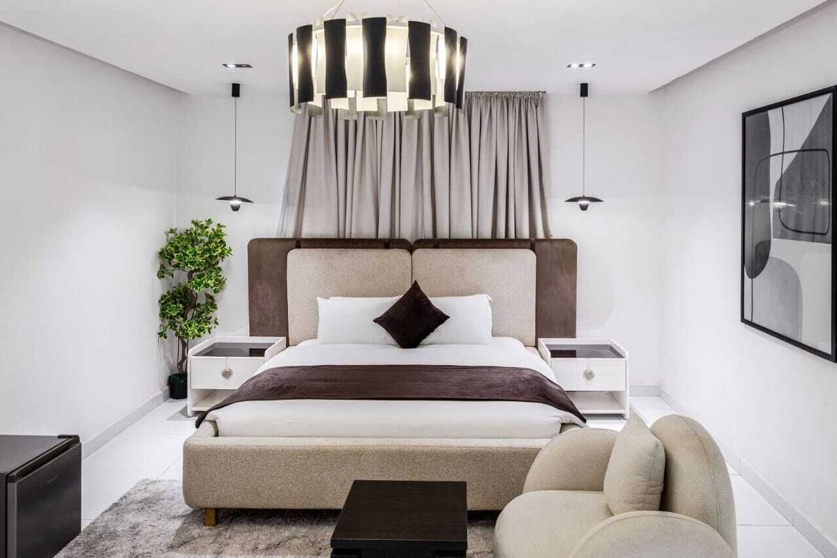 Un dormitorio moderno con una cama grande, mesitas de noche, una lámpara de pie y una lámpara colgante.