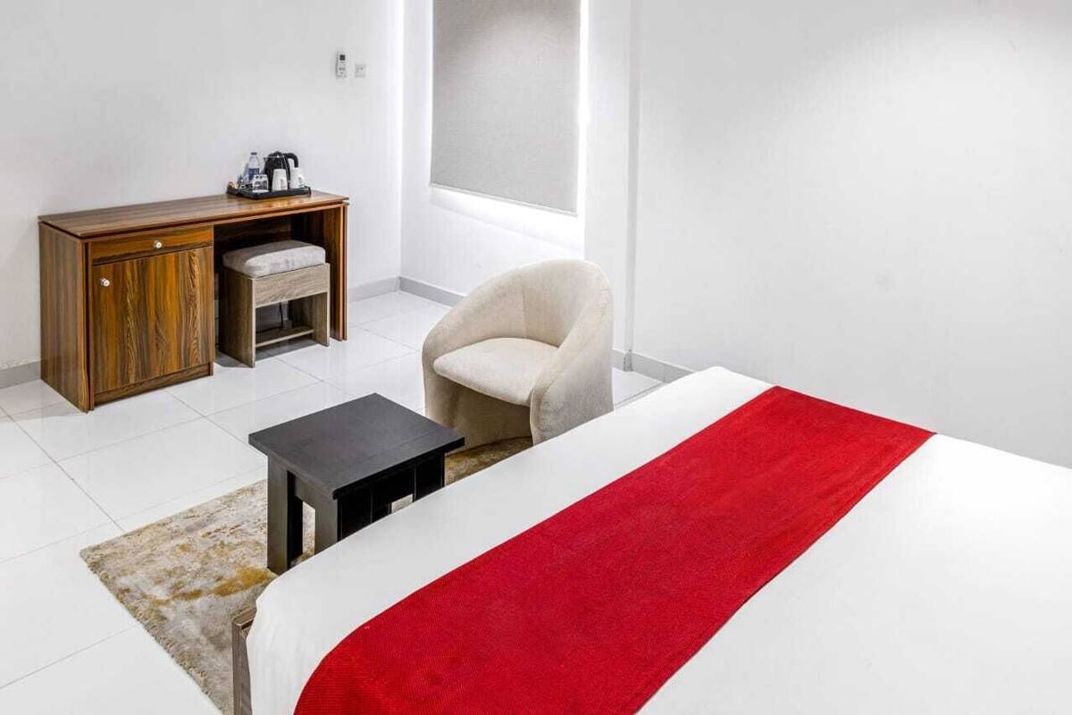 Una habitación de hotel con una cama, un escritorio pequeño, una silla y una ventana.