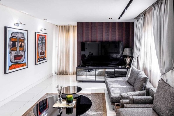 A modern living room with a sofa, a coffee table, and artwork on the wall. - Eterniti By Amber (Lagos)