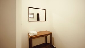 A room with a wooden bench, a framed mirror, and a white wall. - 3-bedroom house in peaceful Alappuzha with AC comfort (Alappuzha)