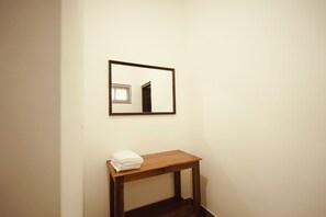 A room with a wooden bench, a framed mirror, and a white wall. - 3-bedroom house in peaceful Alappuzha with AC comfort (Alappuzha)