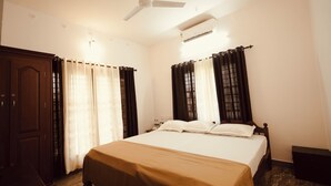 A hotel room with a bed, curtains, a ceiling fan, and an air conditioning unit. - 3-bedroom house in peaceful Alappuzha with AC comfort (Alappuzha)