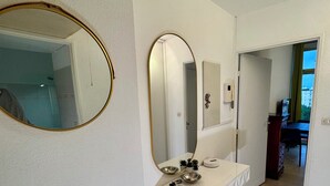 Ett badrum med ett vitt handfat, två speglar och en toalett.
