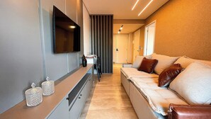 Un pasillo moderno con un sofá, un televisor montado en la pared y una puerta corredera.