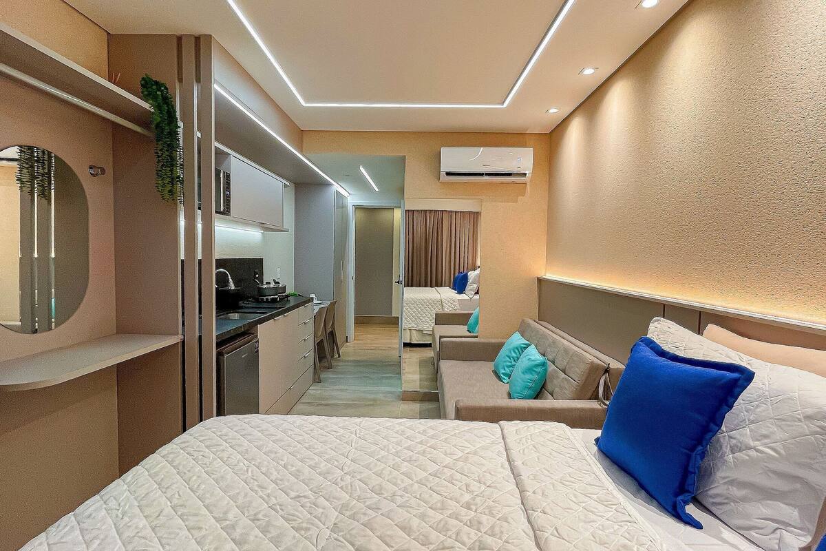 Une chambre d’hôtel moderne équipée d’un grand lit, d’un bureau et d’une kitchenette.
