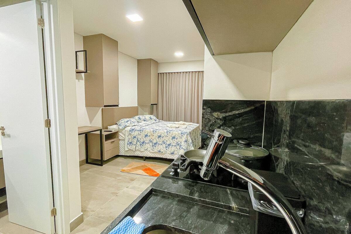 Une chambre d’hôtel de taille réduite, comprenant un lit, un bureau, une salle de bain et une kitchenette.