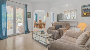 Ein Wohnzimmer mit einem Glastisch, einer Couch und einem Essbereich mit Stühlen und einem Tisch.