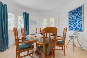 A dining area with wooden chairs, a table set for four, and a high chair.